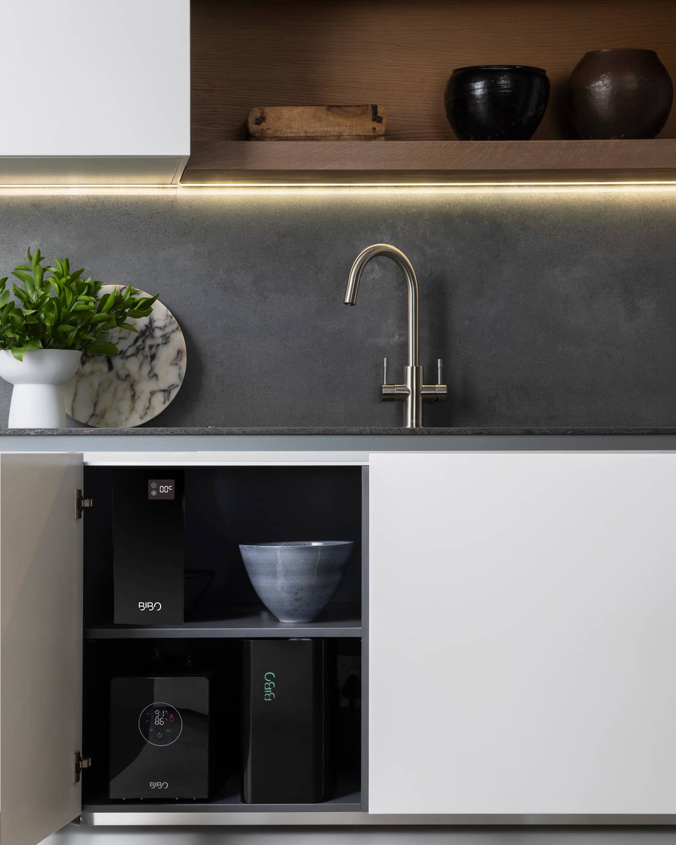 BIBO rock series integrated water system installed beneath a modern white kitchen countertop with concealed cabinetry. -1